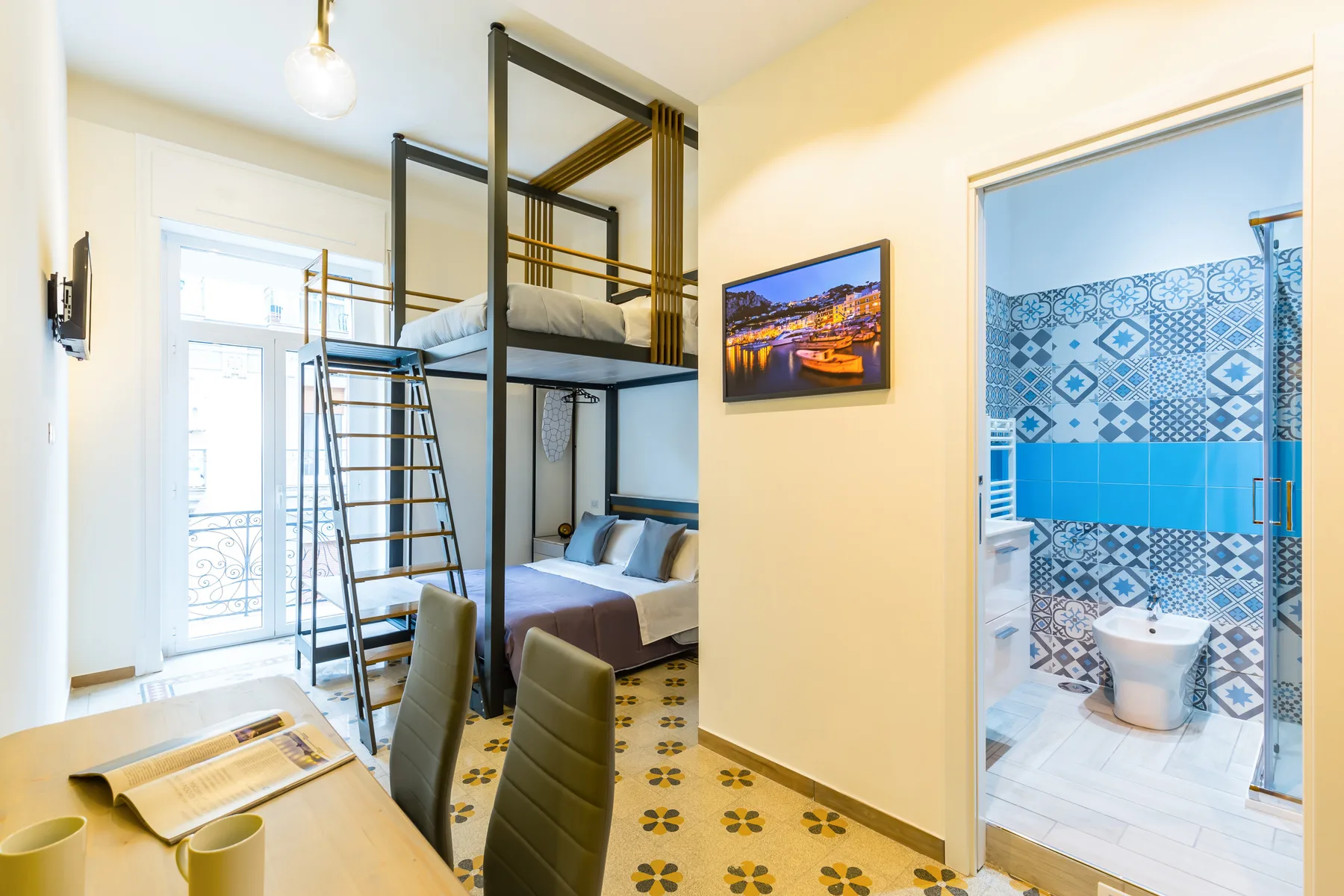 Un dormitorio luminoso con una zona elevada para dormir y una puerta abierta a un baño con azulejos.