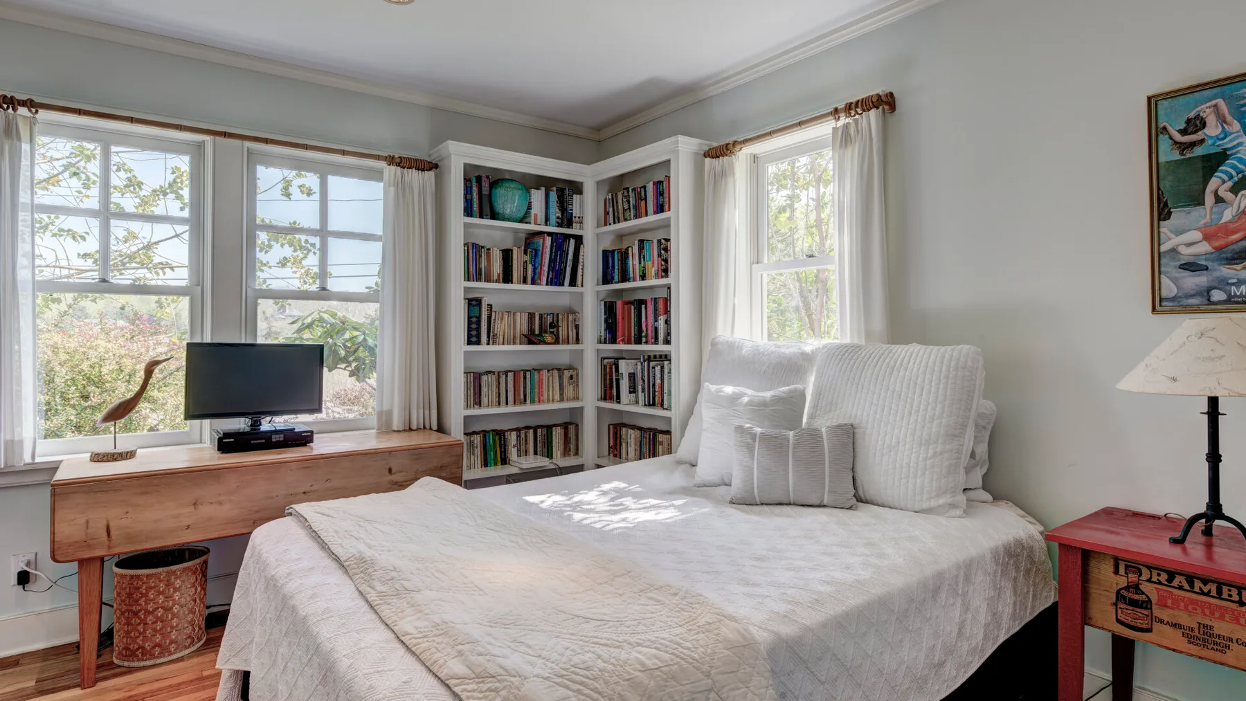 Un dormitorio con una cama arreglada, estanterías y ventanas.