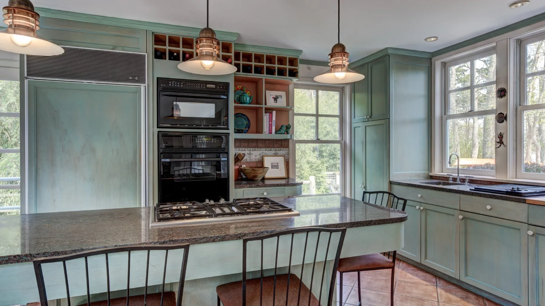 Una cocina luminosa con gabinetes verde claro, una estufa y una isla.