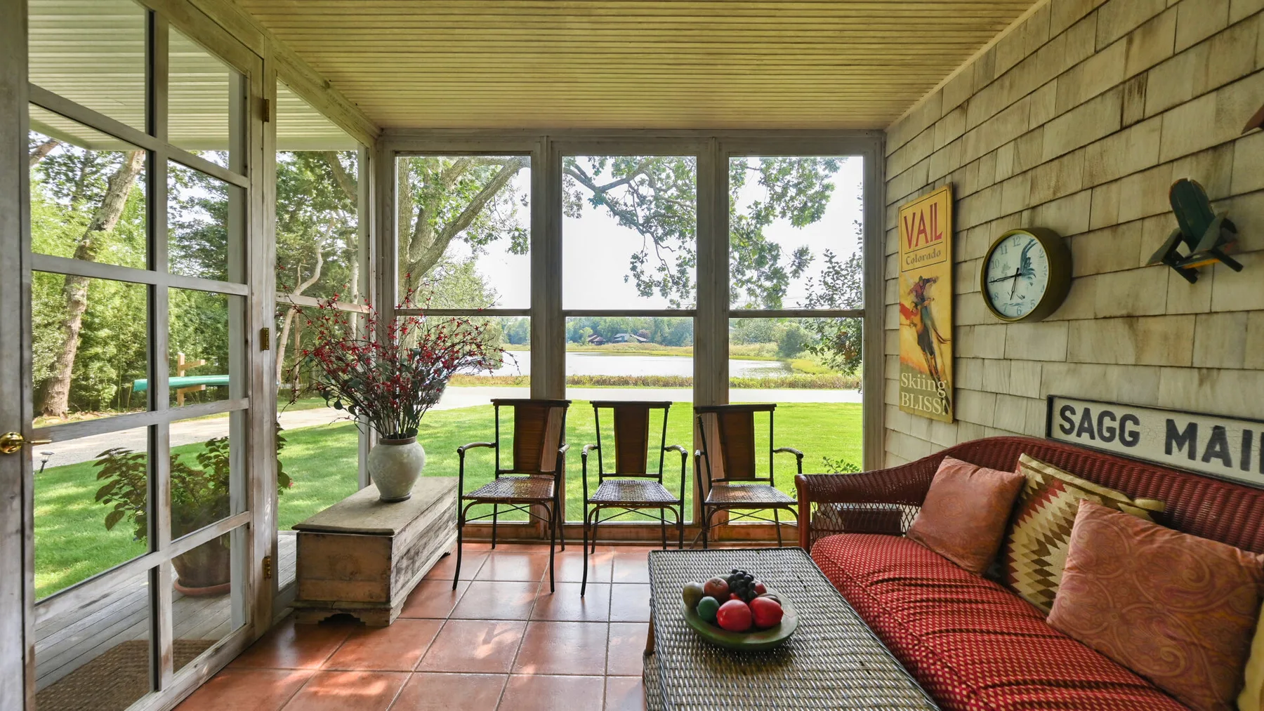 Un solárium con un sofá rojo y una mesa de comedor junto a grandes ventanas.