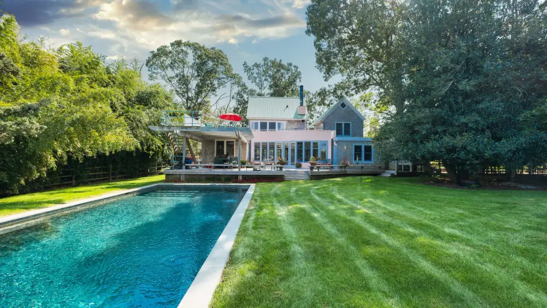 Una casa da a una piscina y a un amplio césped verde.