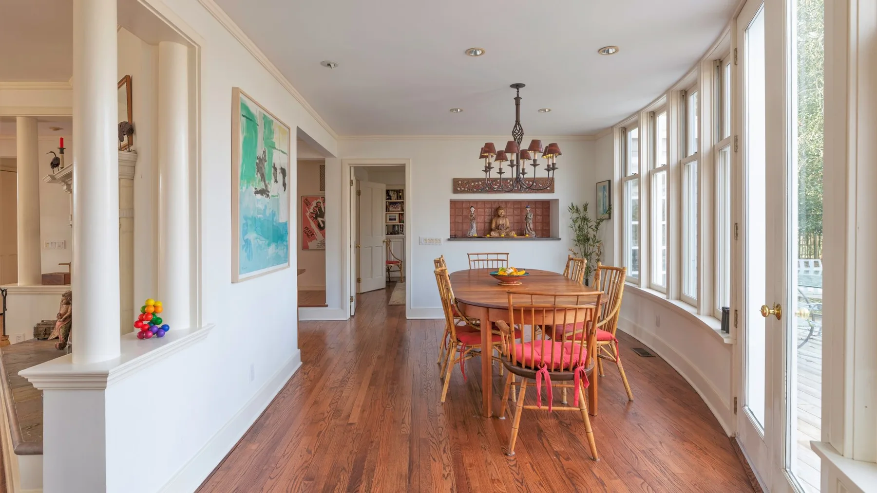Un comedor con una mesa de madera y grandes ventanas a un lado.