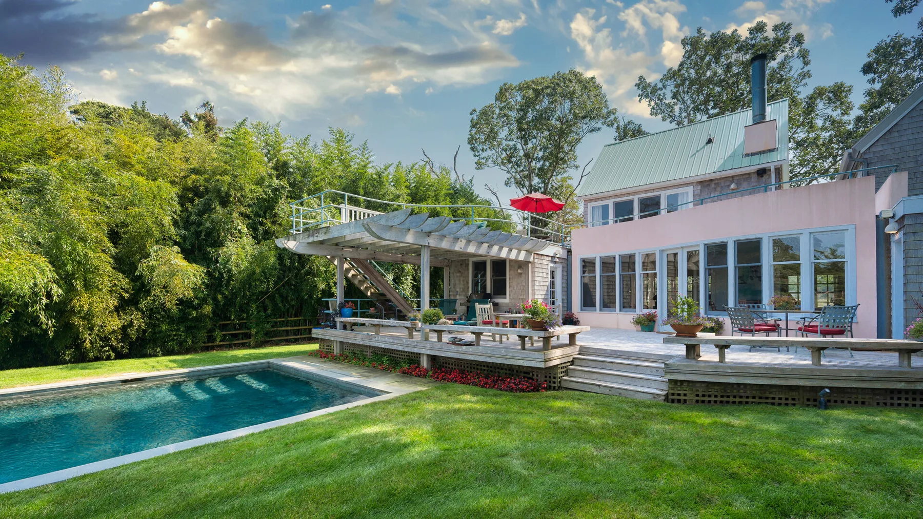 Una casa moderna da a una piscina y una terraza elevada.