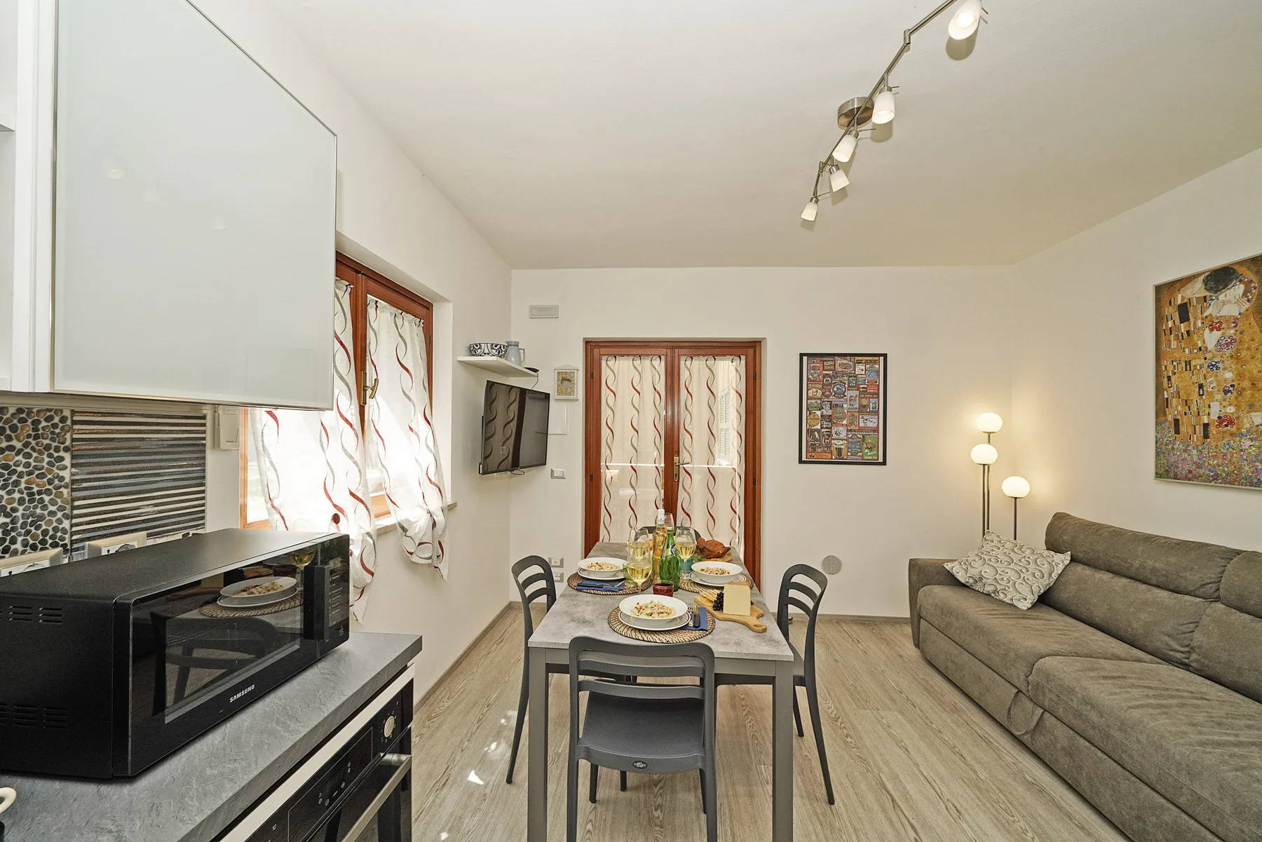 Un comedor con la mesa puesta, asientos y electrodomésticos de cocina.