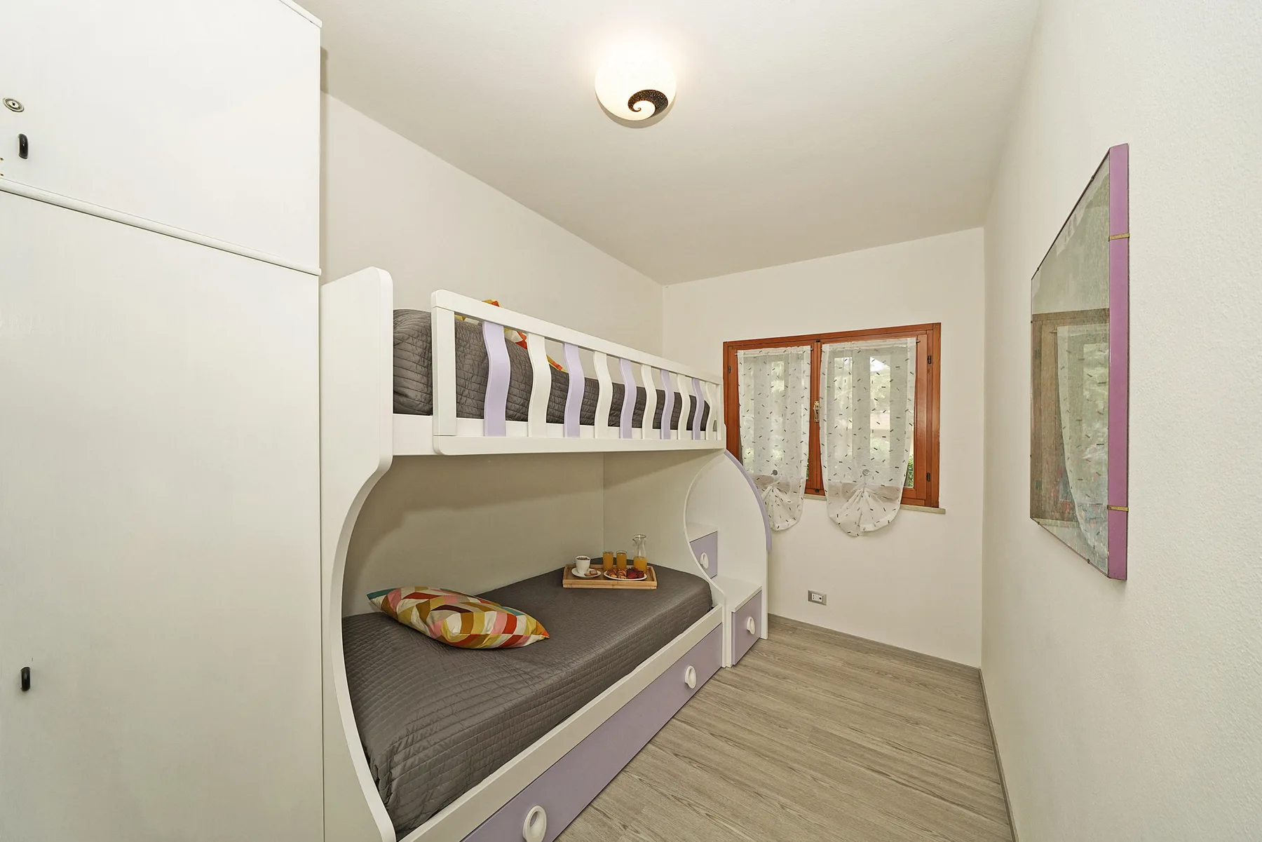Un dormitorio con una litera, ropa de cama colorida y una ventana.