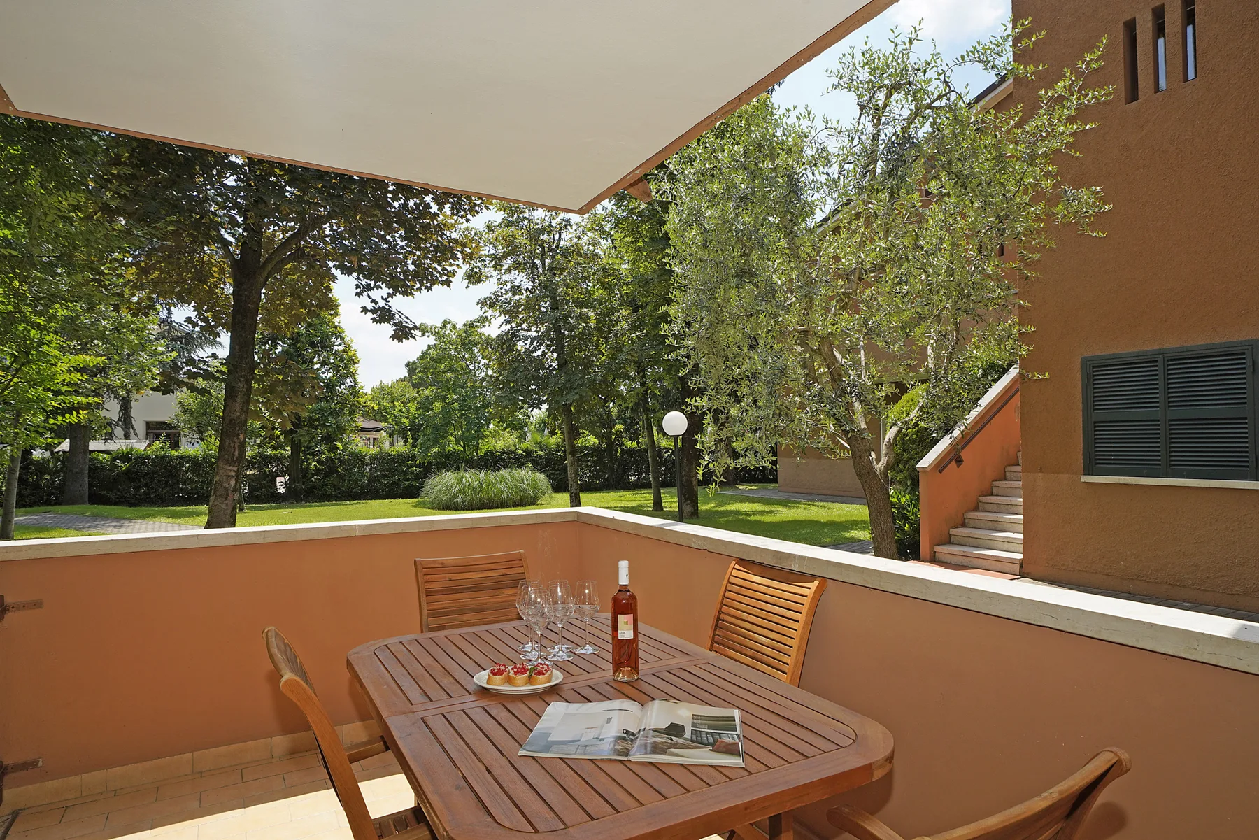 Una zona de comedor al aire libre con una mesa de madera y árboles alrededor.
