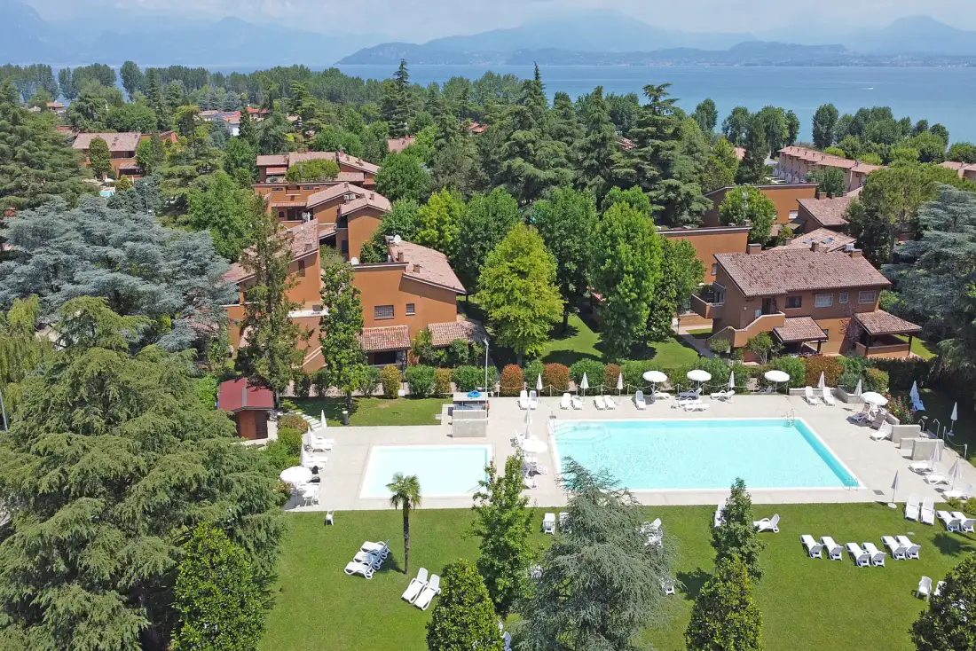 Vista aérea de una piscina y edificios rodeados de árboles.