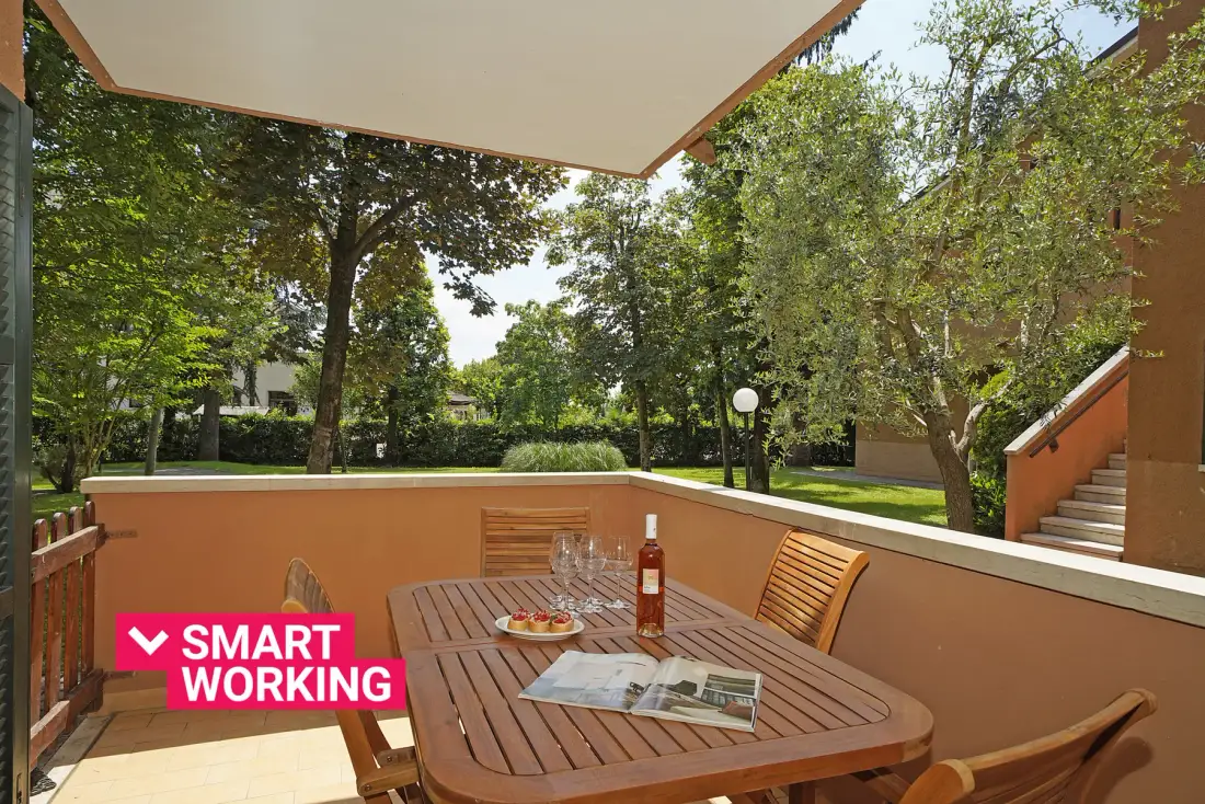 Una zona de comedor exterior cubierta con una mesa de madera y vistas al jardín.