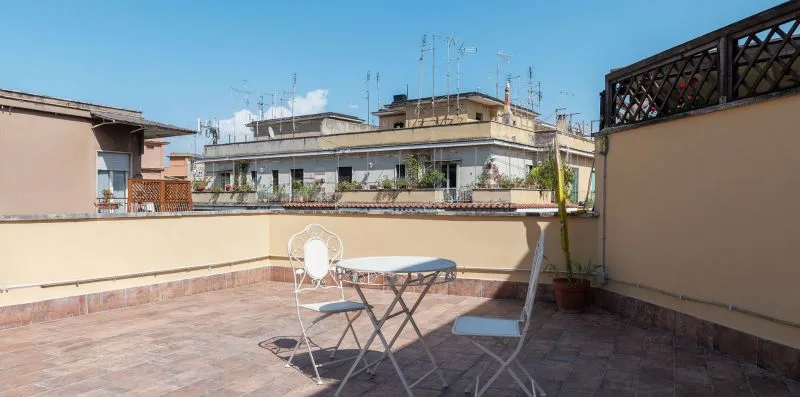 Una terraza soleada en la azotea con una mesa pequeña y asientos.