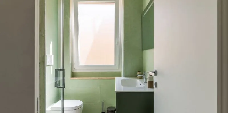 Un baño con lavabo, inodoro y una ventana esmerilada.