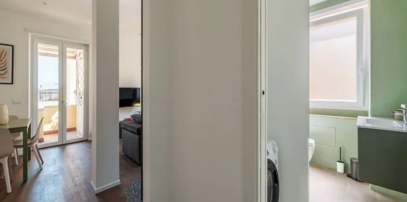 Un interior luminoso conecta un comedor, una sala de estar y un baño.