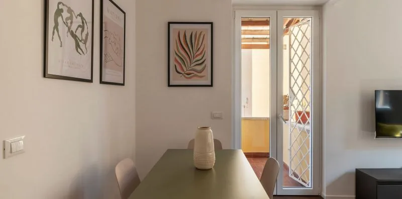Un comedor con una mesa, cuadros enmarcados y una puerta de vidrio.