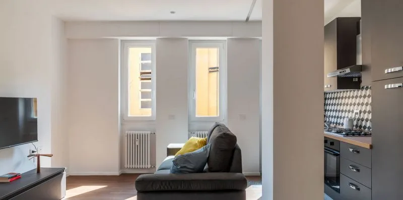 Una sala de estar con asientos junto a una cocina compacta.