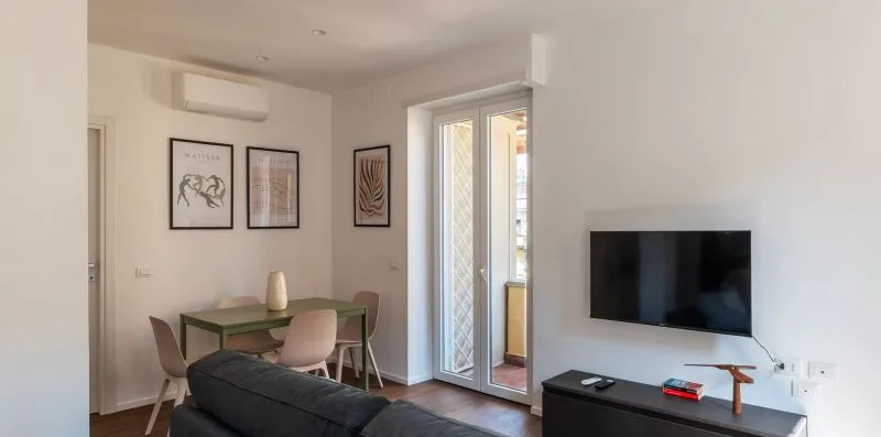 Una zona de comedor y estar con una mesa, asientos y un televisor.