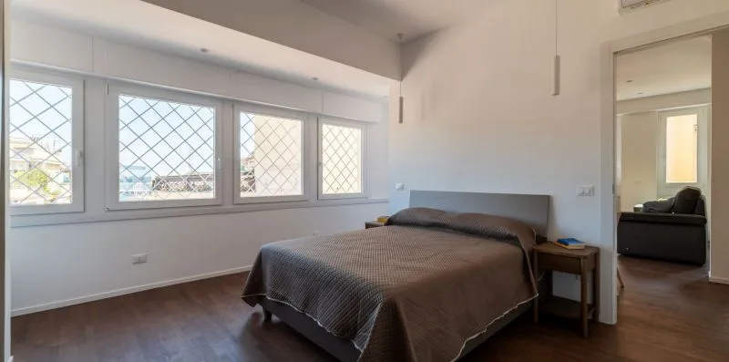 Un dormitorio con una cama junto a una fila de ventanas.