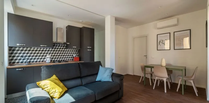 Una sala de estar con un sofá oscuro junto a una mesa de comedor.
