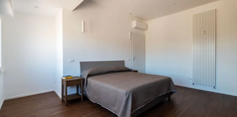 Un dormitorio con una cama, una mesita de noche y un aire acondicionado de pared.