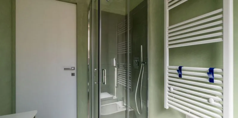 Un baño con una ducha de vidrio y un toallero calefactable en la pared.