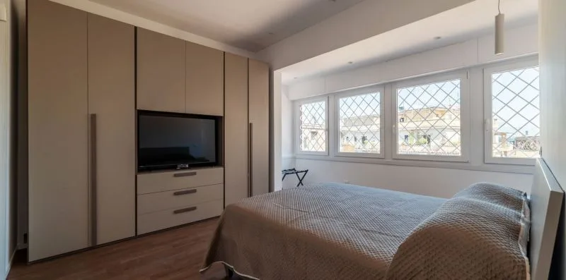 Un dormitorio con una cama, armarios empotrados y varias ventanas.