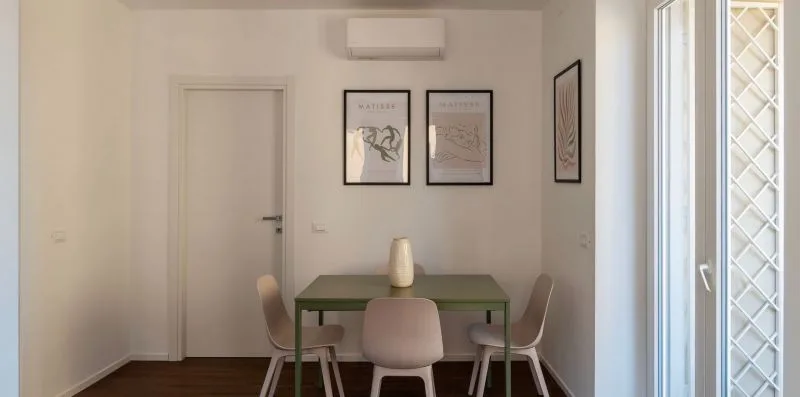 Comedor con una mesa verde y cuadros enmarcados en la pared.