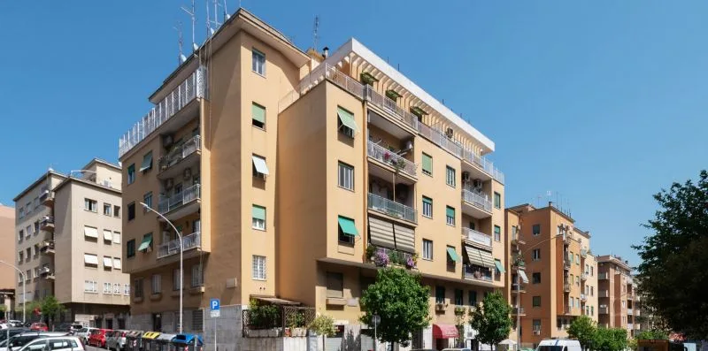 Una hilera de edificios de apartamentos bordea una calle urbana bajo un cielo despejado.