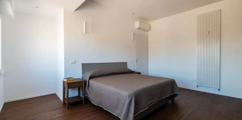 Un dormitorio con una cama doble y un radiador alto junto a la pared.