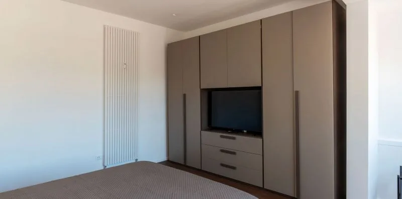 Un dormitorio con armarios empotrados y un televisor sobre cajones.