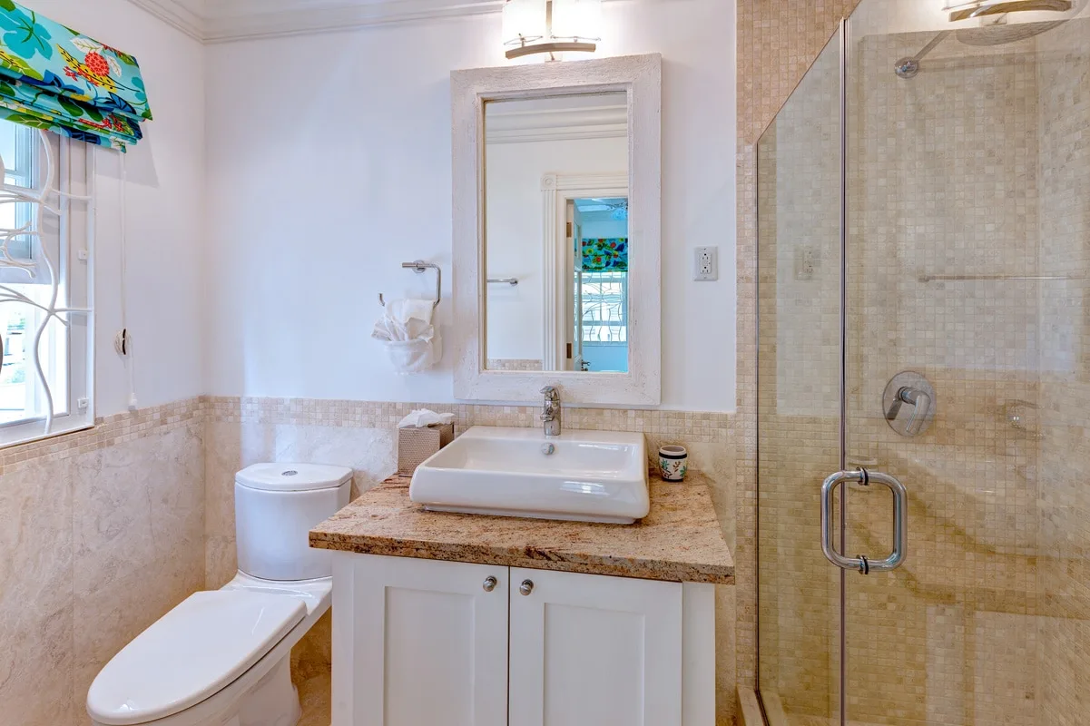 A bathroom with a sink, toilet, and glass-enclosed shower.