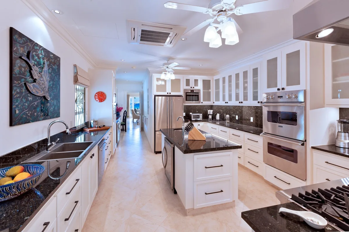 A bright kitchen with white cabinetry, dark countertops, and a central island.