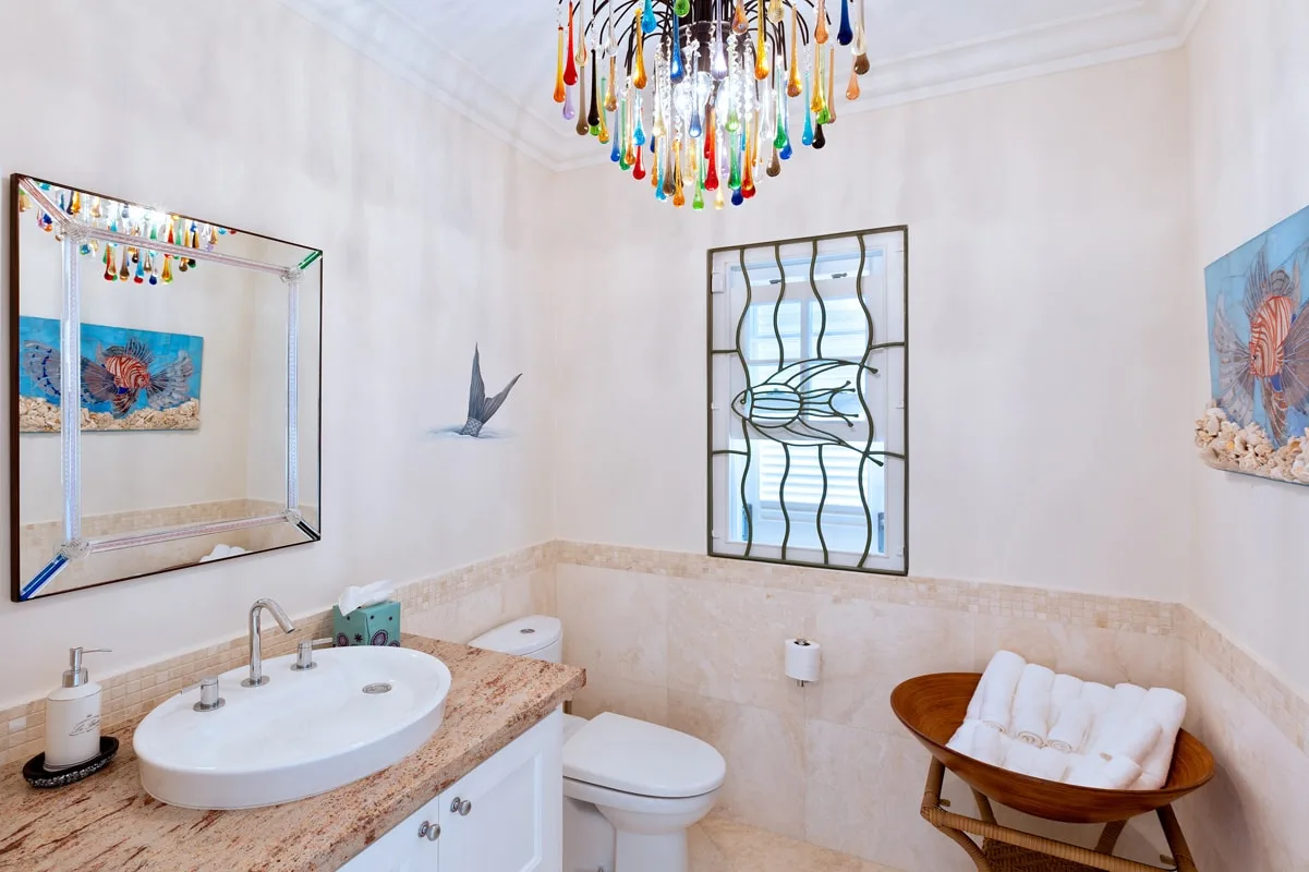 A bathroom with a sink, toilet, and colorful hanging light fixture.