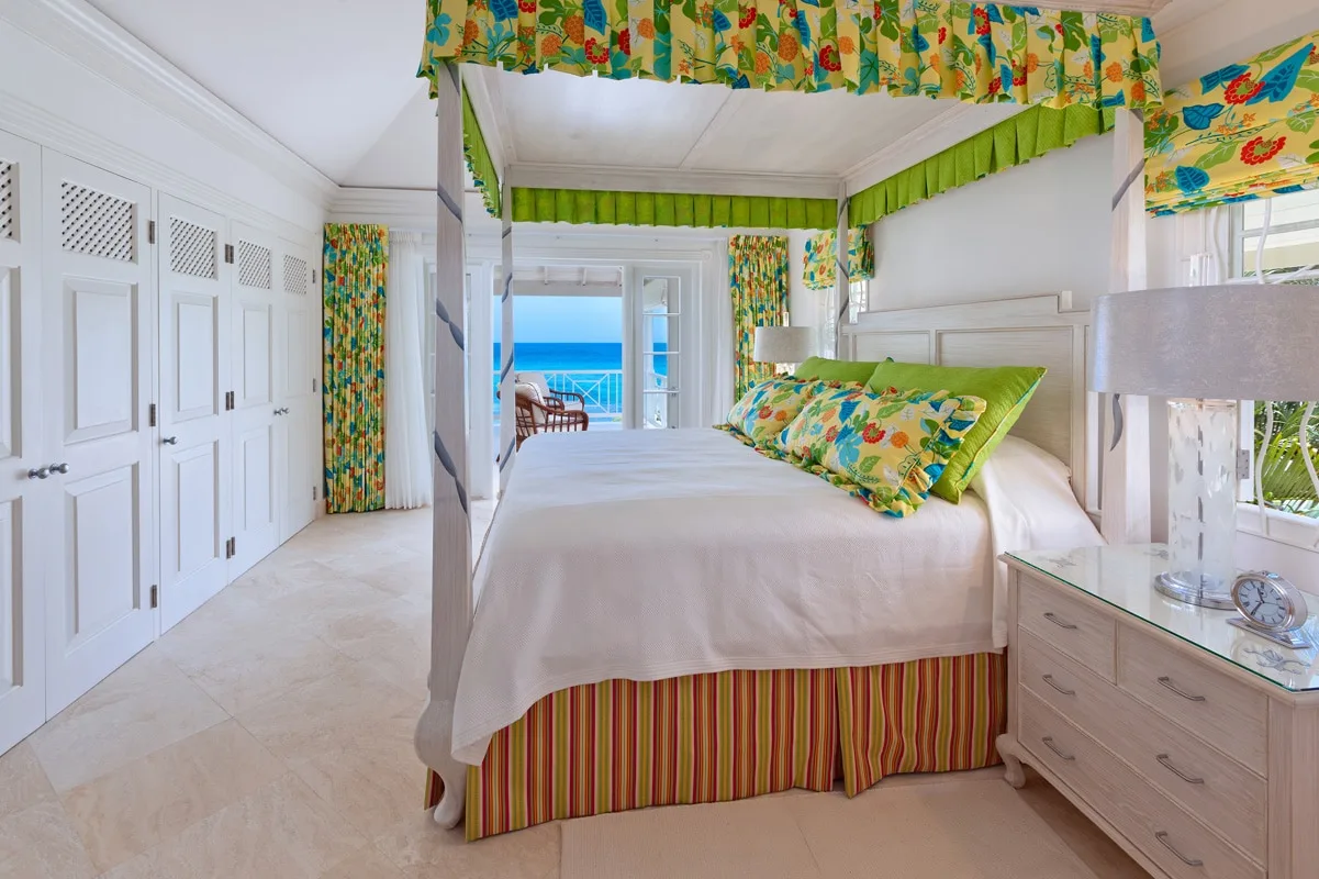A bright bedroom with a canopy bed and colorful floral bedding.