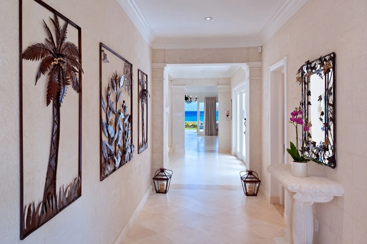 A bright hallway with framed wall art and a view toward the sea.