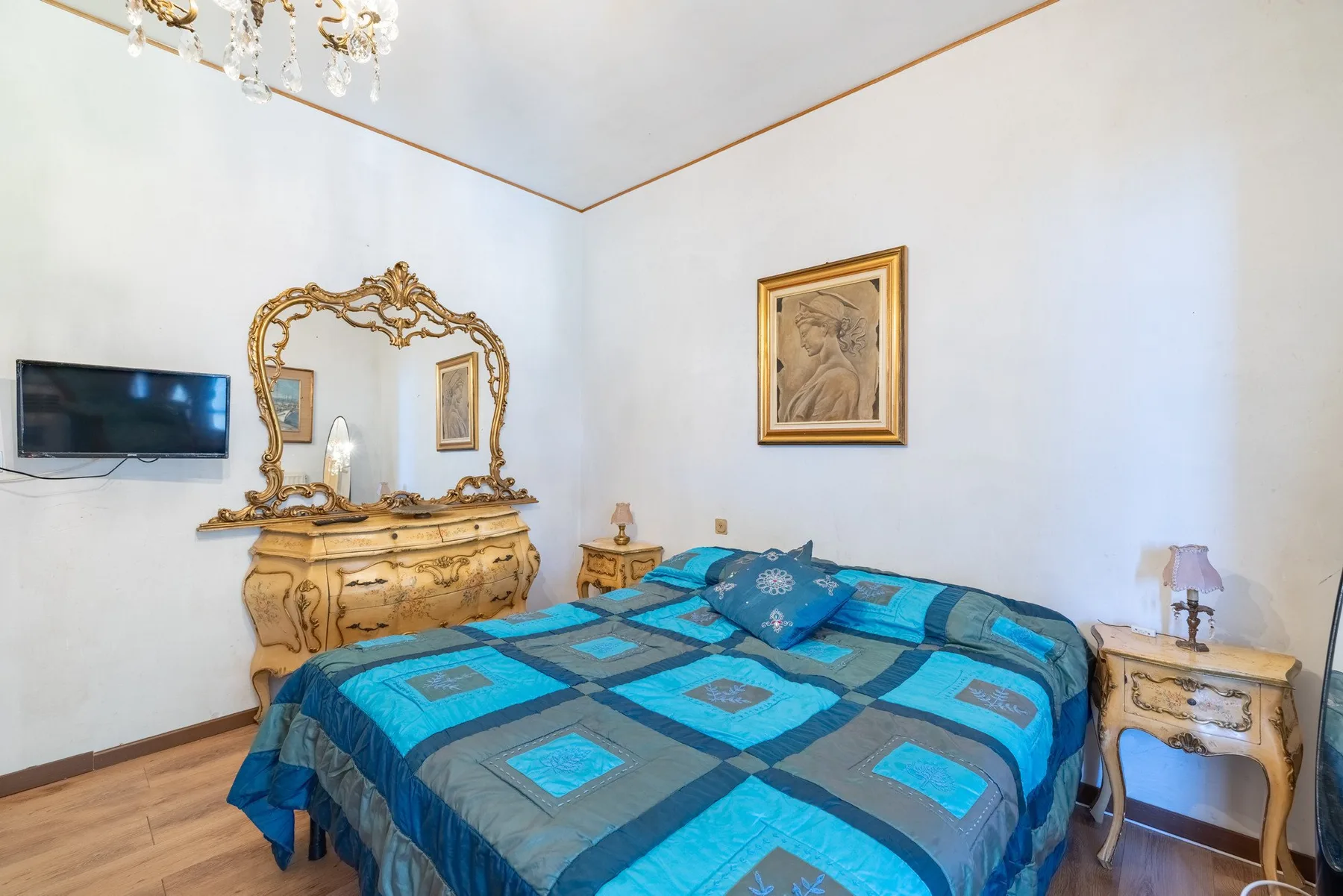 A bedroom with a bed covered in a blue geometric-patterned bedspread.