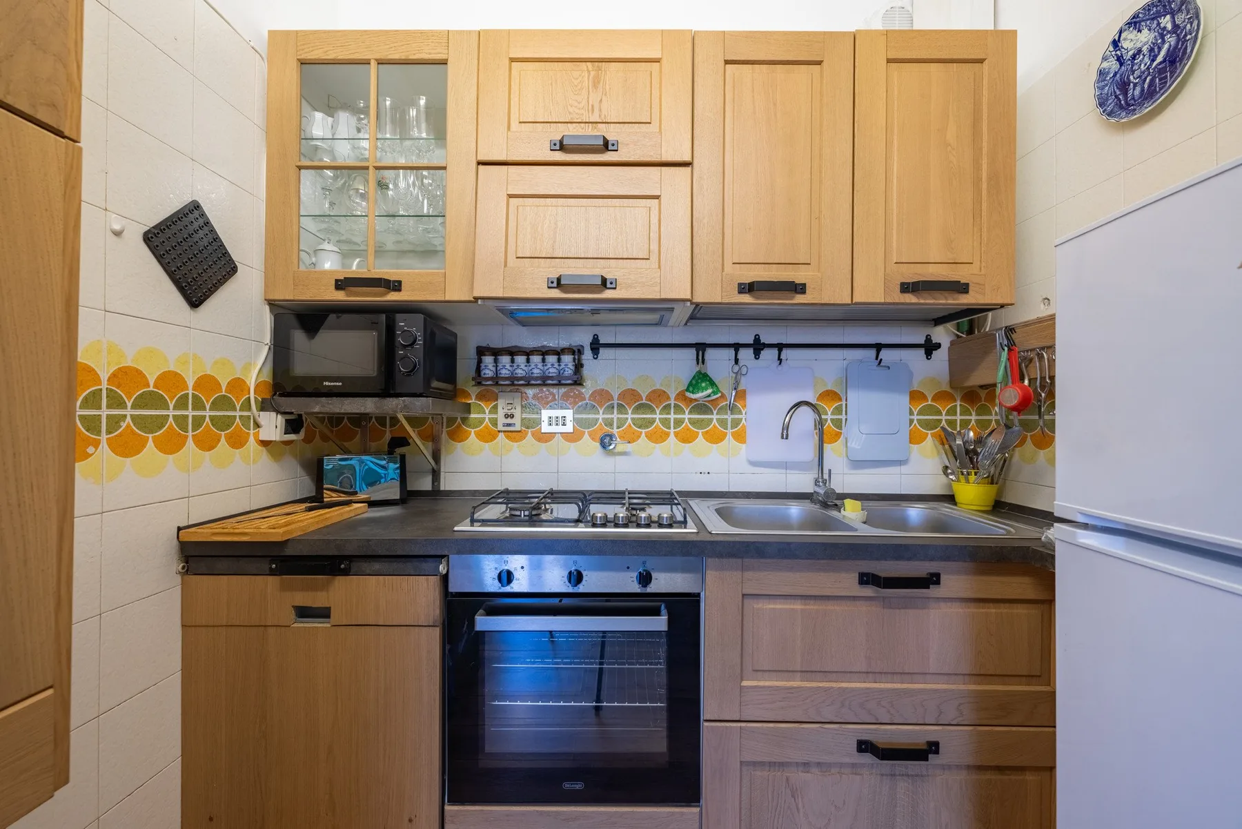 A compact kitchen with wooden cabinets, a stovetop, and a sink.