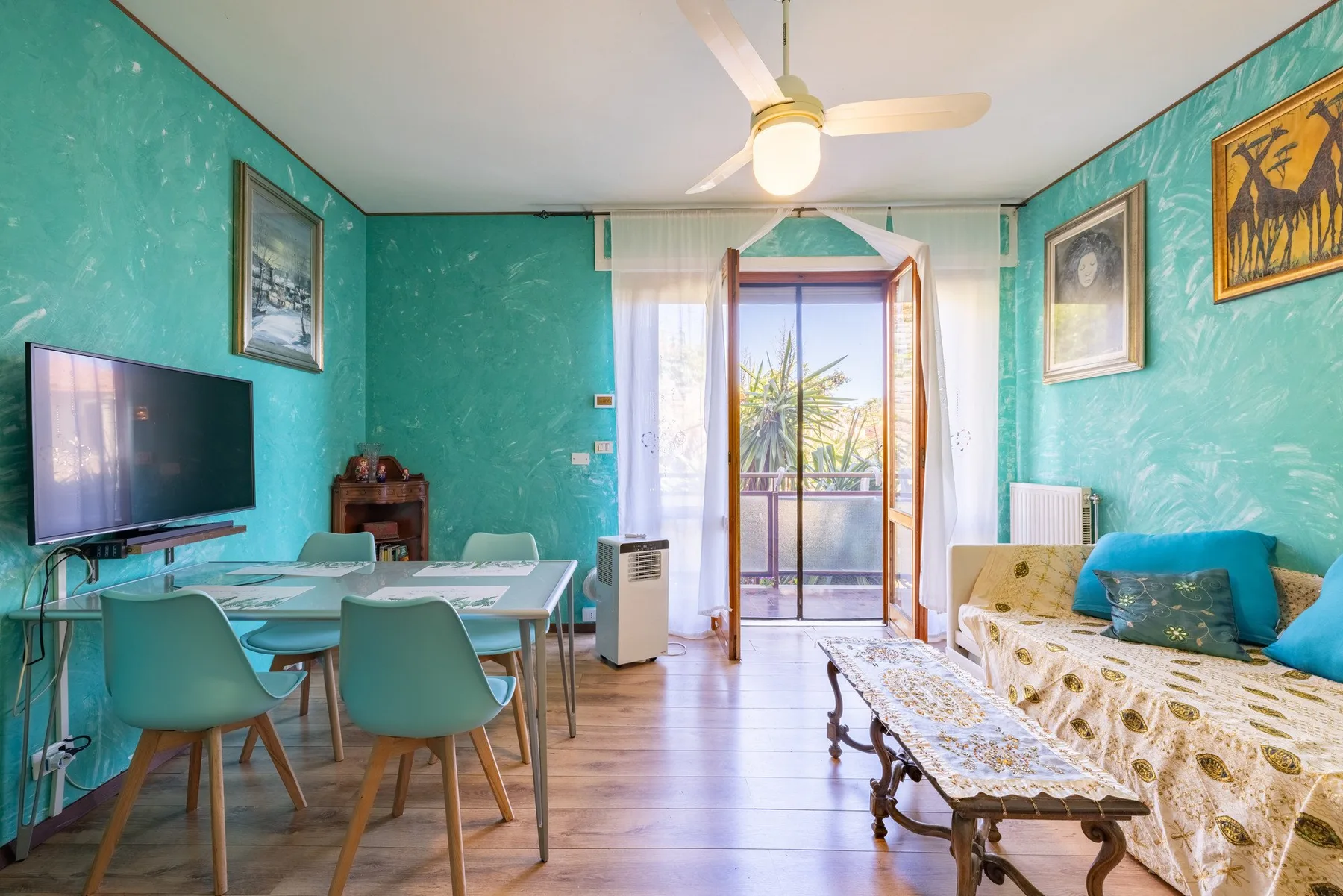 A living room with a dining table, seating, and glass doors opening to a balcony.