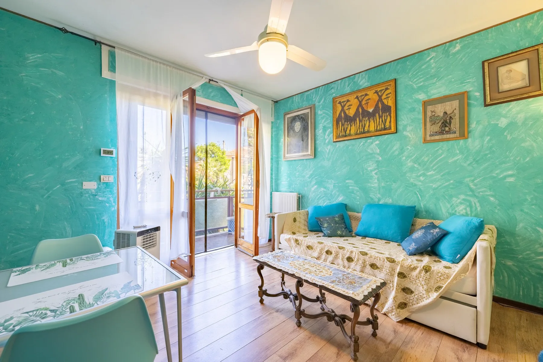 Living room with turquoise walls, seating, and a glass-topped coffee table.