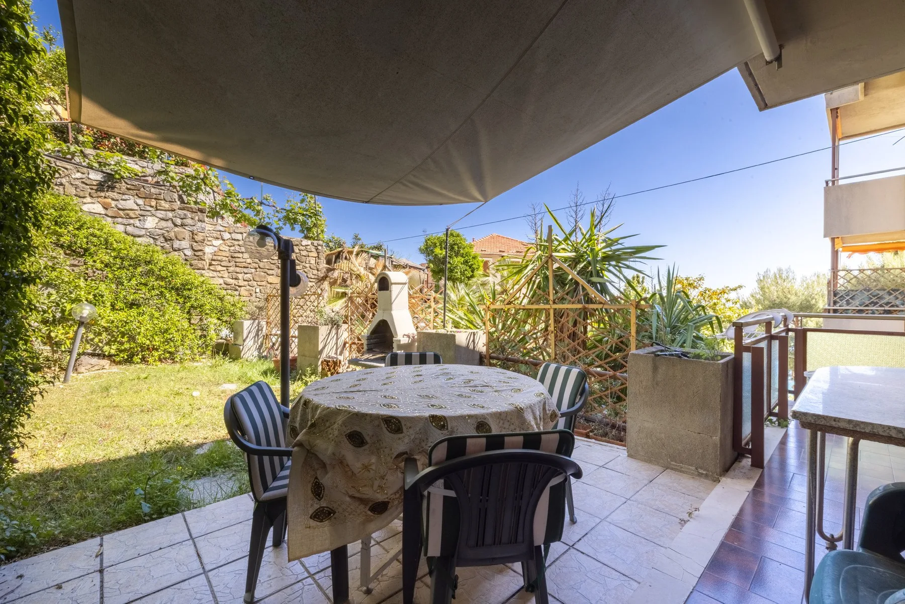 A tiled outdoor dining area with a table and chairs beneath a canopy.