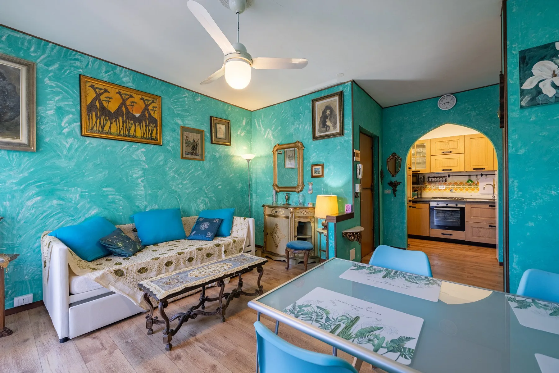 A colorful living and dining area features seating, a table, and an arched kitchen opening.
