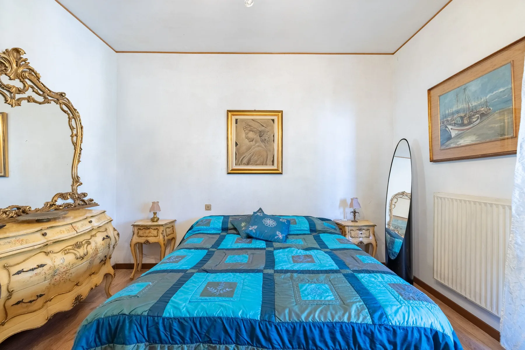 A bedroom with a bed covered by a blue patterned quilt.