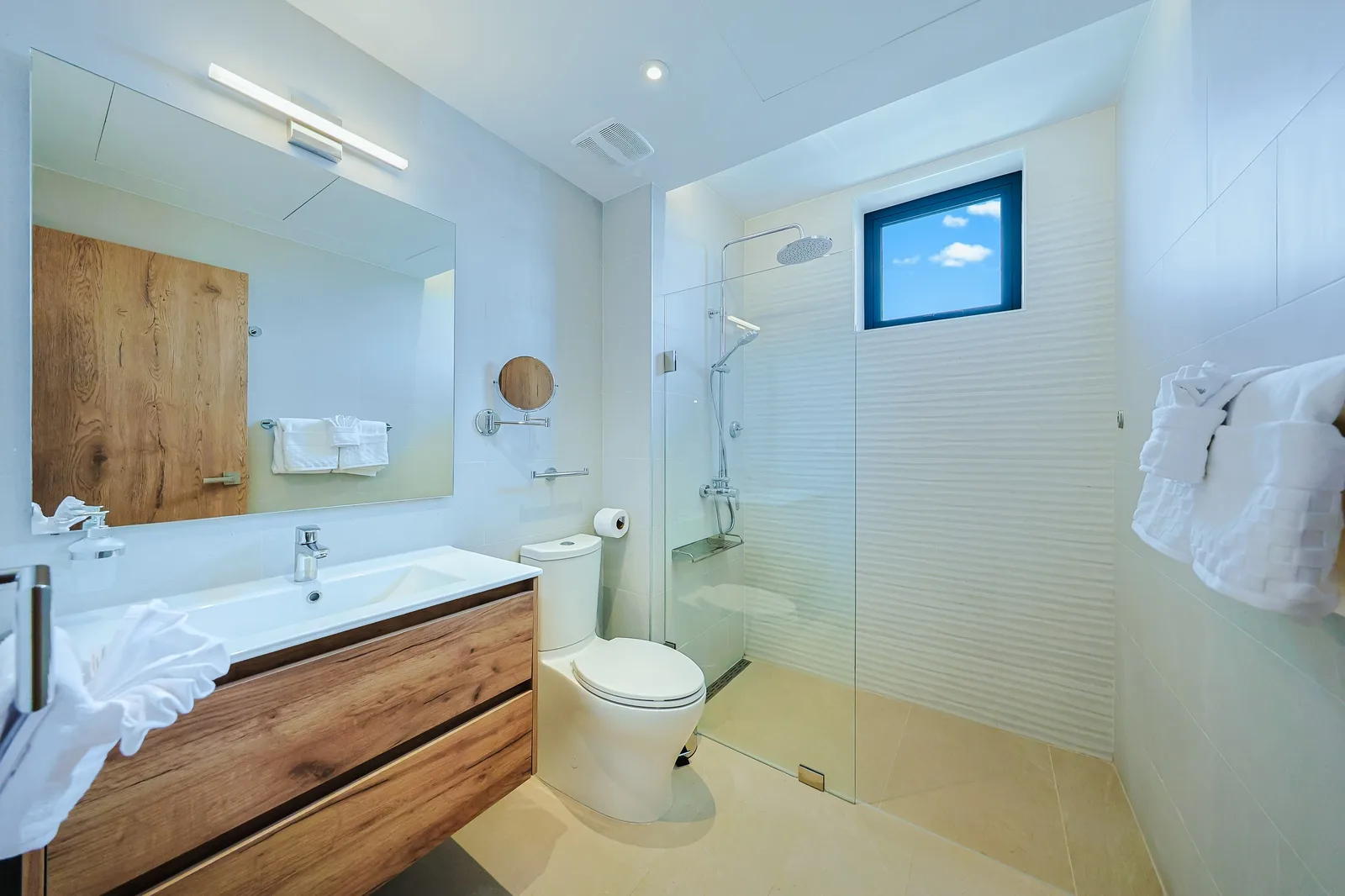 Enjoy a bright, modern bathroom with a sleek glass-enclosed shower, fresh linens, and warm wooden accents that create a soothing escape after your day of exploring.