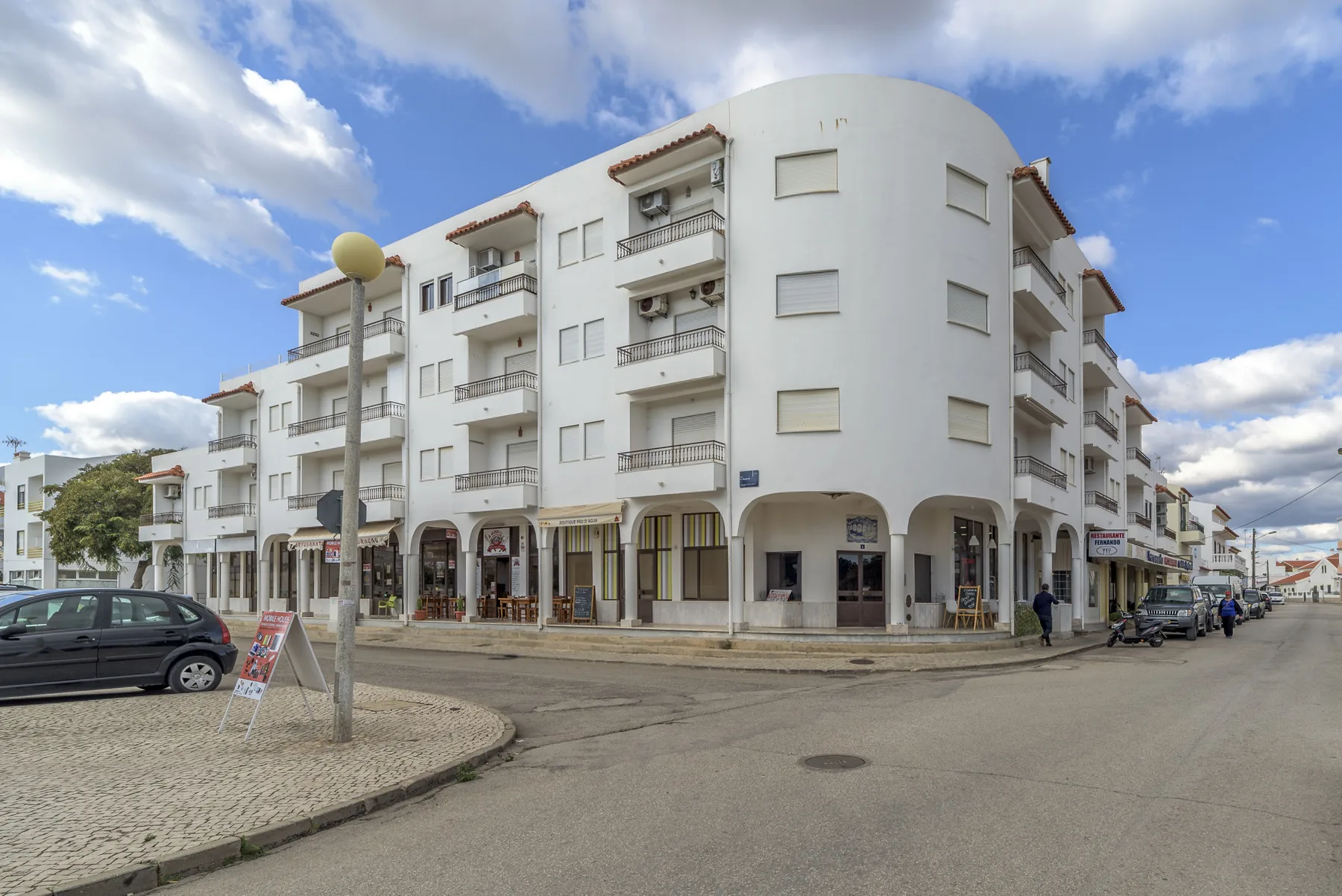 Un edificio blanco de varias plantas con tiendas en la planta baja está en una esquina.