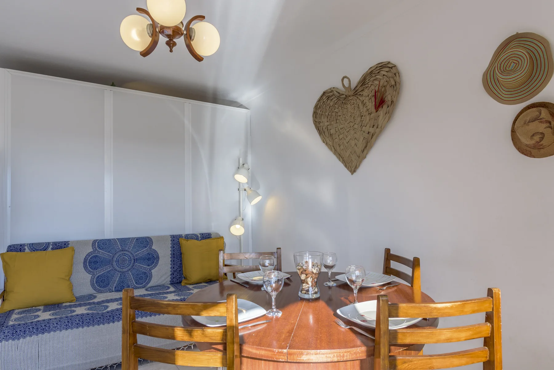 Comedor con una mesa de madera preparada junto a un sofá azul estampado.