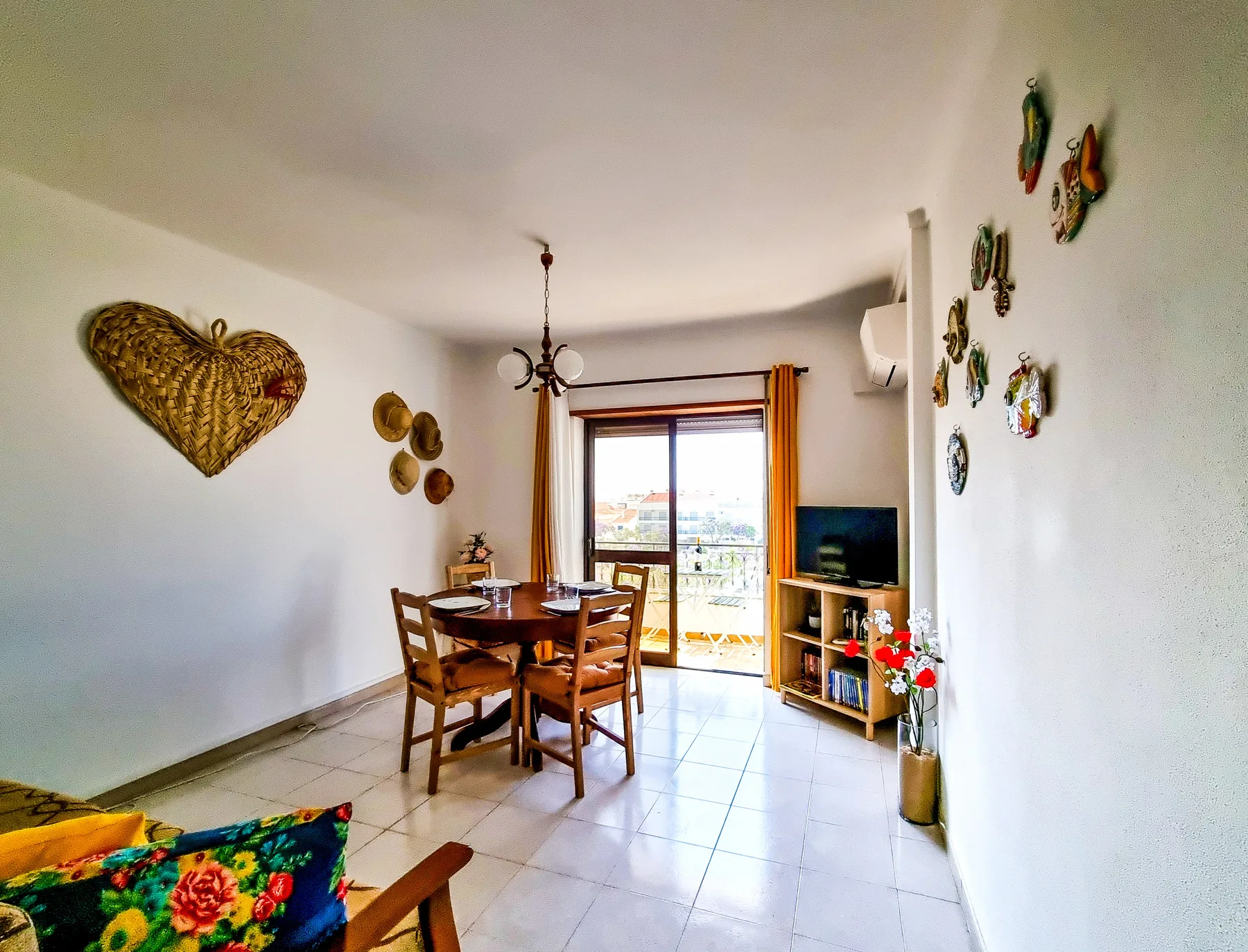 Una luminosa zona de comedor y estar con una mesa de madera y puertas al balcón.