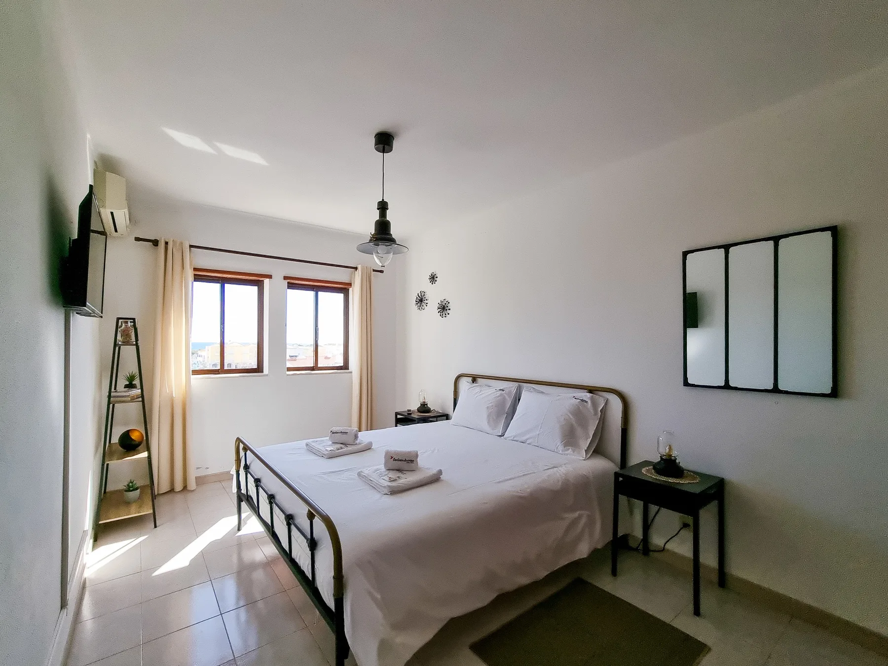 Un dormitorio con una cama bien hecha y dos ventanas.