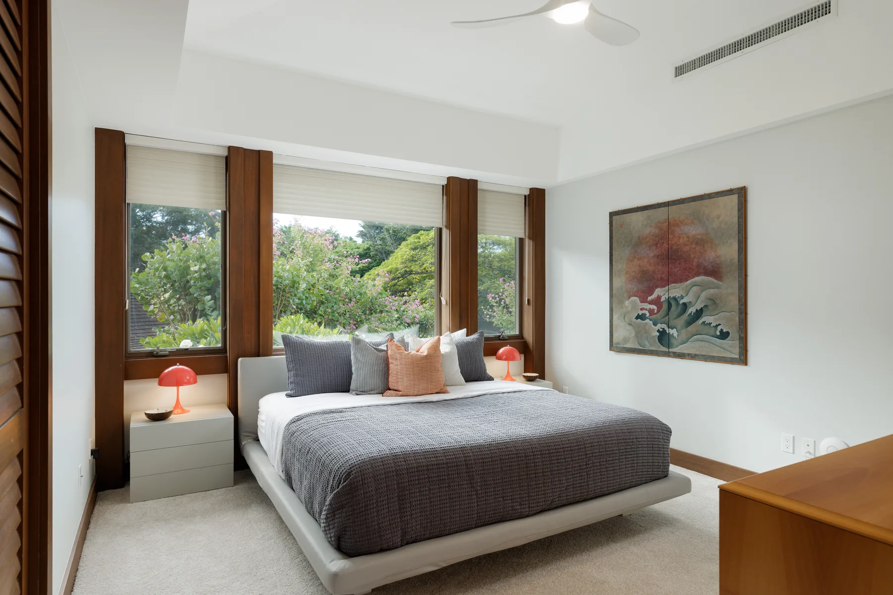 Un dormitorio con una cama bajo amplias ventanas que dan a la vegetación.