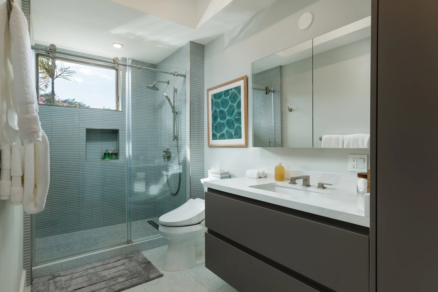 Un baño moderno con una ducha de vidrio y un lavabo amplio.