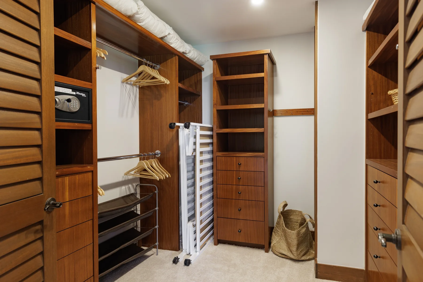 Un vestidor con estantes de madera, cajones y barras para colgar ropa.