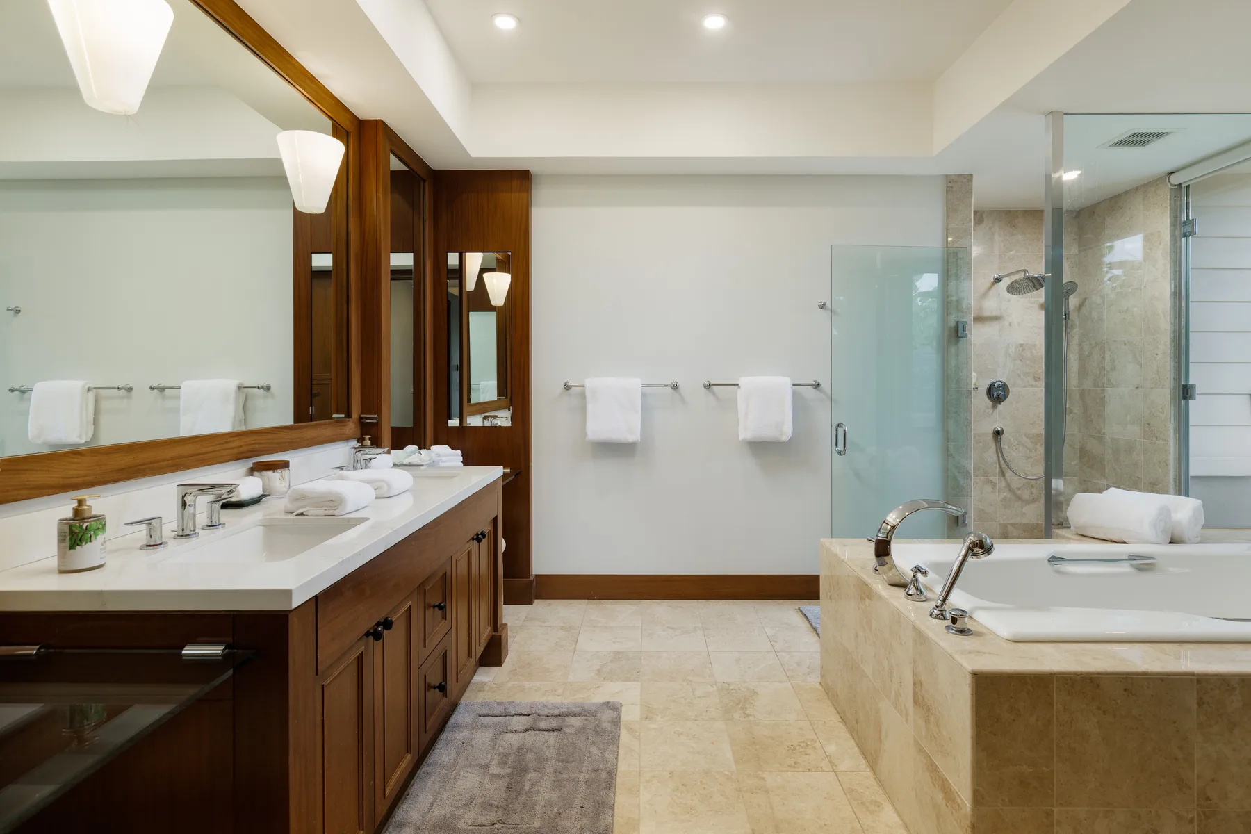 Un baño amplio con un tocador largo y una bañera junto a una ducha de vidrio.