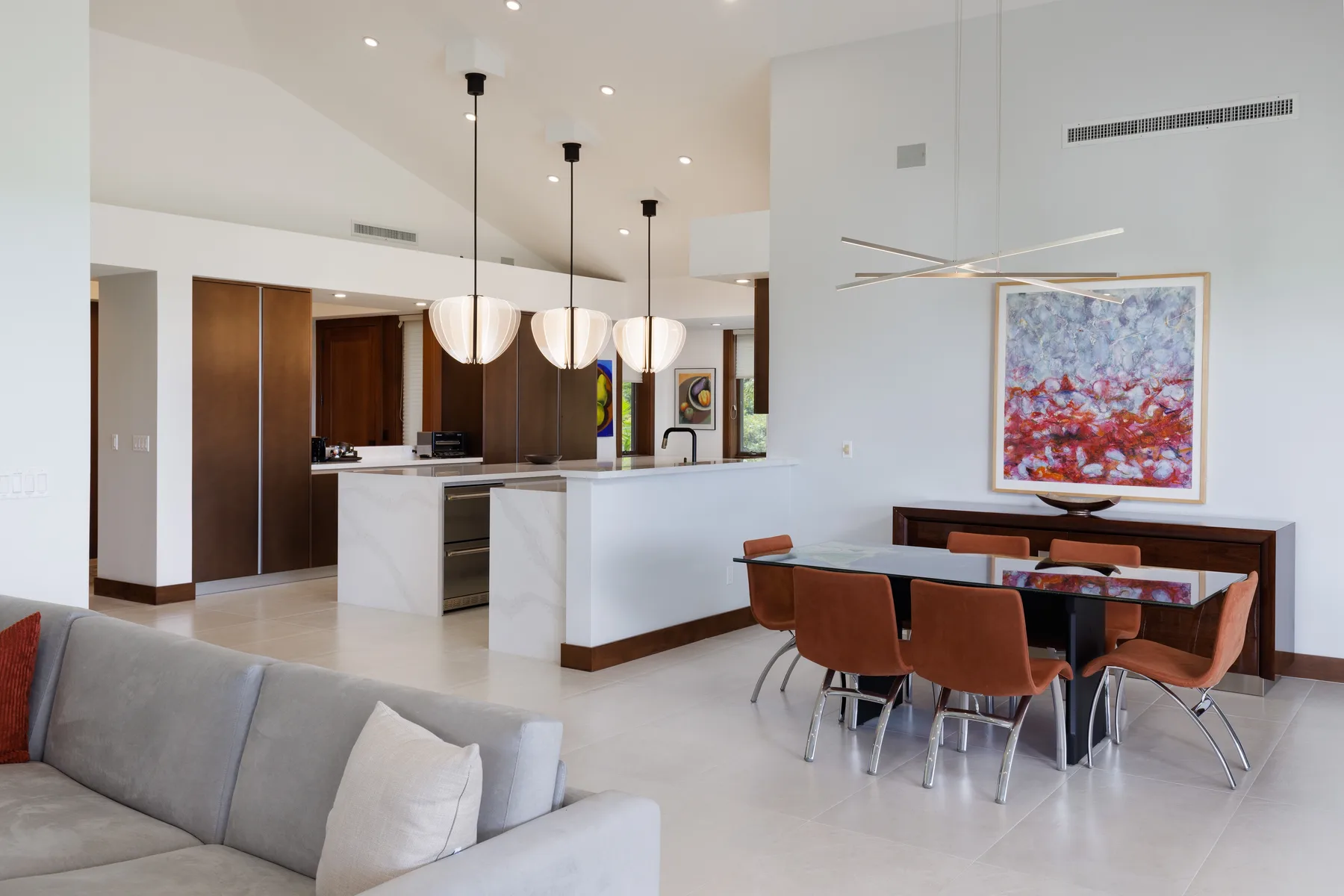 Un espacio abierto de sala y comedor con cocina y una obra de arte colorida.
