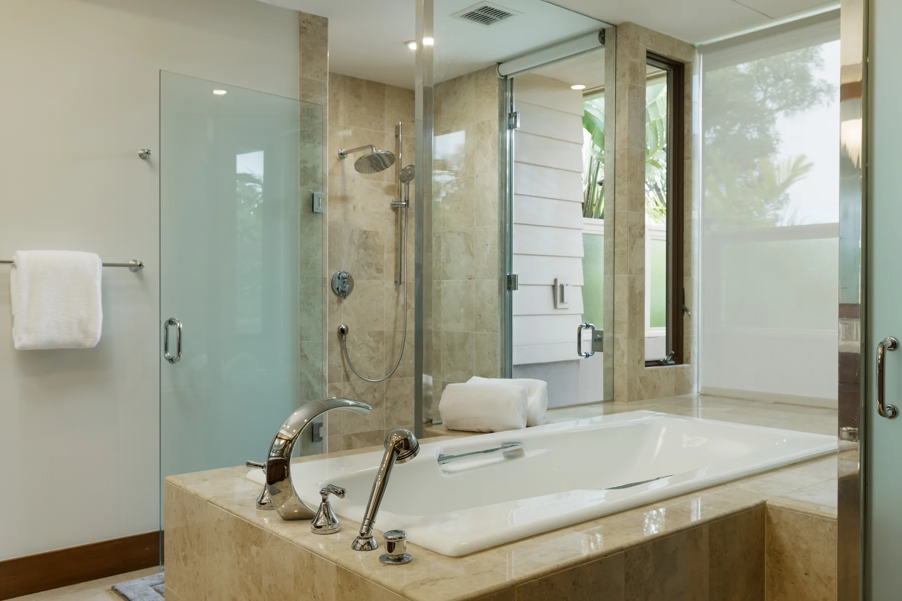 Un baño luminoso con bañera, ducha de vidrio y ventanas amplias.